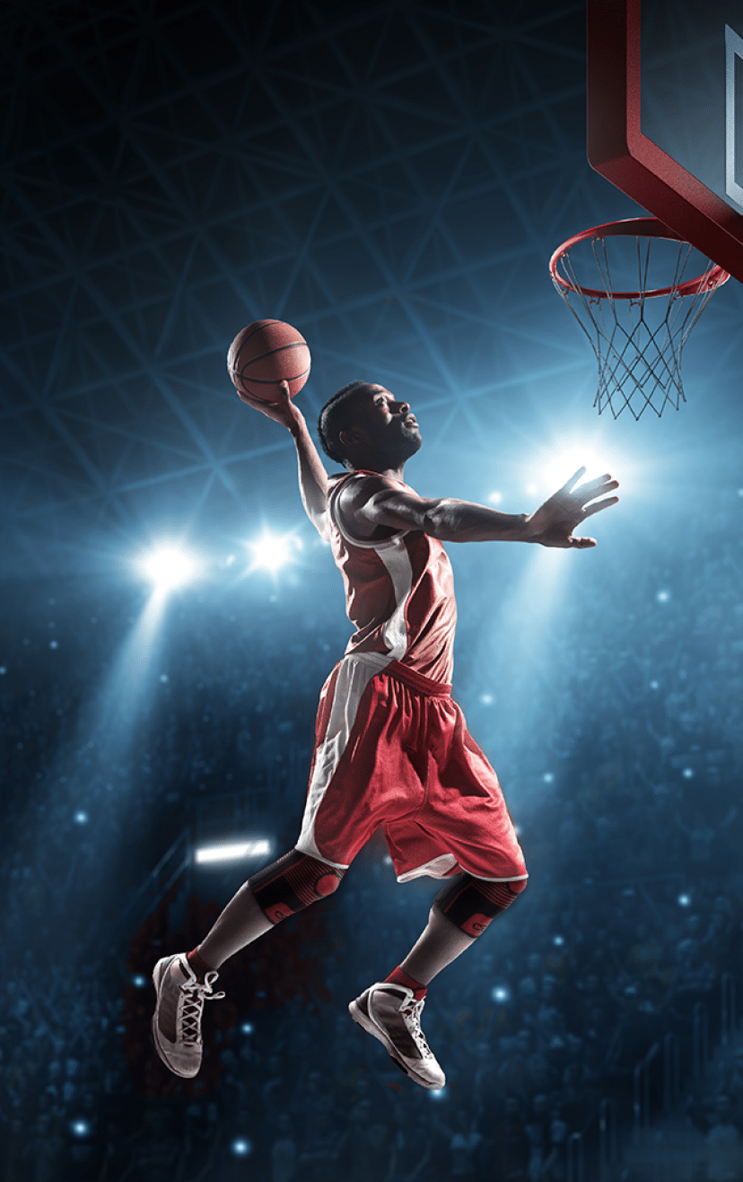 Close up image of professional basketball player about to do slam dunk during basketball game in floodlight basketball court
